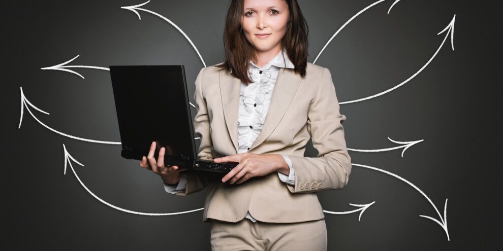 Frau in Anzug mit Laptop und Pfeilen